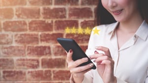 Women holding phone rating a telecoms digital customer experience 